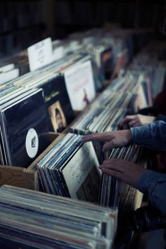 two people reaching for records in an old record store's display case filled with cds