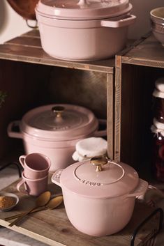 pink pots and pans sit on wooden shelves