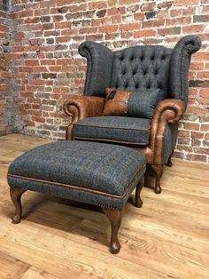 an upholstered chair and footstool in front of a red brick wall