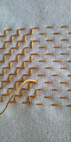 an orange thread is hooked up to a piece of fabric that has been stitched together