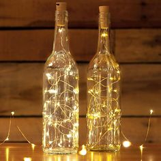 two bottles with fairy lights in them sitting on a table