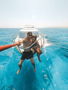 two people on a boat in the water with their arms around each other as they jump into the air