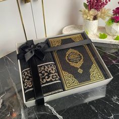 a black and gold book with a bow sitting on top of a table next to flowers