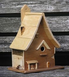 a wooden birdhouse sitting on top of a wooden bench