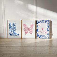 three framed pictures on the floor in front of a white wall with blue and pink designs