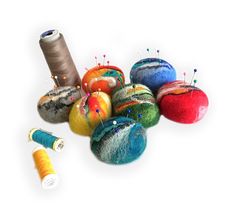 several different colored balls of yarn next to spools of thread and sewing needles