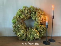 a wreath and two candles on a table