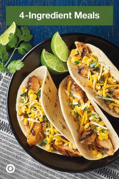 three chicken tacos on a plate with limes and cilantro