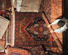 a man standing on top of a pile of rugs