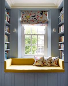 a window seat in front of a book shelf filled with books