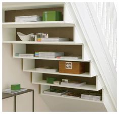 a white book shelf sitting under a stair case