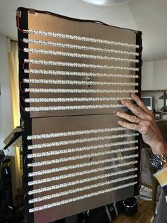 a man is holding up an electronic board with many wires attached to it and his hands are on top of the board