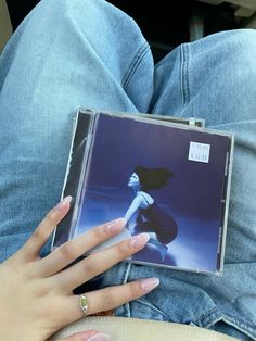 a person holding a cd in their lap with both hands on the back of it