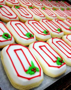 decorated cookies sitting on top of a baking sheet covered in white frosting and red icing