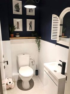 a white toilet sitting inside of a bathroom next to a sink and mirror with pictures on the wall