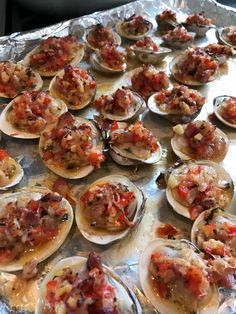 an aluminum tray filled with open oysters covered in toppings