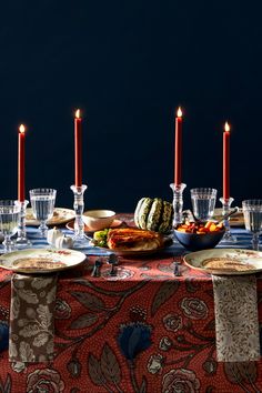 a table topped with plates and glasses filled with food next to candles on top of a table