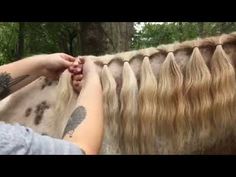 a woman with long blonde hair standing next to a horse's tail and braiding it