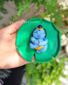 a small figurine sitting on top of a green object in someone's hand