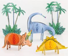 three dinosaurs are standing next to each other in front of some trees and palm trees