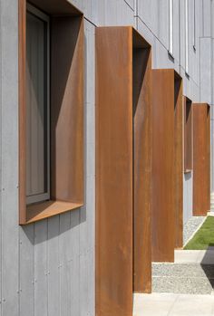 a row of metal buildings with open windows on each side and grass in the background