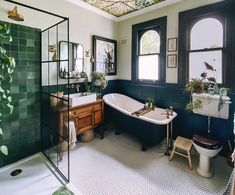 an old fashioned bathroom with green tiles on the ceiling and black bathtub in the corner