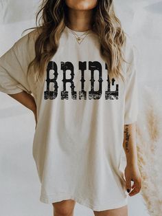 a woman wearing a t - shirt with the word bride printed in black on it