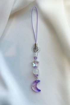 a purple necklace with white beads and a mermaid tail hanging from it's side