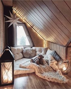 an attic bedroom with wooden walls and lights on the ceiling, a large bed covered in blankets