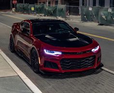 a red chevrolet camaro is parked on the street