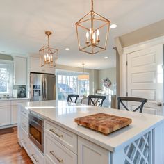 a large kitchen with an island and wooden cutting board on the counter top in front of it