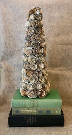 a stack of books sitting on top of each other next to a statue made out of rolled paper