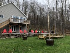 a house in the woods with red chairs and a picnic table set up outside it