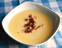 a white bowl filled with soup on top of a blue and white checkered table cloth