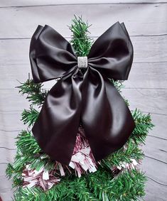 a christmas tree with a large bow on it's top and pine needles in the bottom