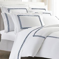 a bed with white sheets and blue trimmings on the pillowcase is shown