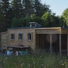 a small wooden house sitting on top of a lush green field next to trees and bushes