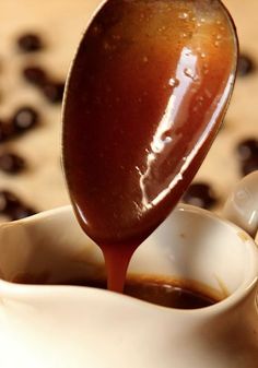 a spoon pouring coffee into a white cup