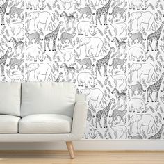 a white couch sitting in front of a wall with black and white animals on it