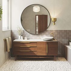 a bathroom with a large round mirror above the sink and wooden cabinetry, along with a white bathtub