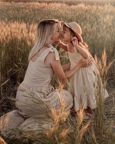 two women sitting in tall grass kissing each other