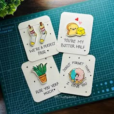 four stickers with words on them sitting on top of a cutting board next to a potted plant