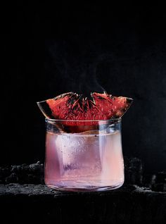 a watermelon slice sitting on top of a pink liquid in a glass vase