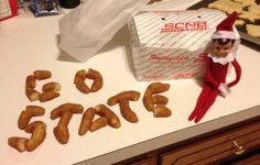 an elf is sitting on the counter next to some doughnuts that spell out go state