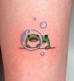 a small frog in a bubble tattoo on the thigh, with bubbles coming out of it