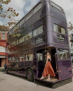 a woman is standing in the open door of a double - decker bus that has been painted purple