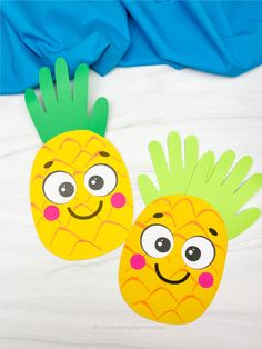 two paper pineapples with googly eyes are on a white sheet and blue sheets