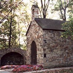 an old stone church surrounded by trees and flowers