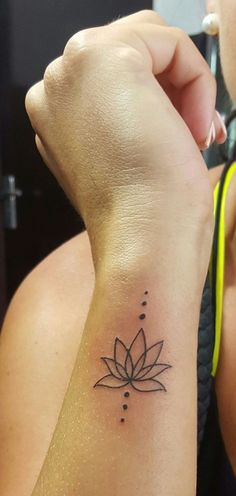 a woman's arm with a small lotus tattoo on the left side of her wrist