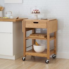 a kitchen cart with food on it in front of a white brick wall and wooden floor